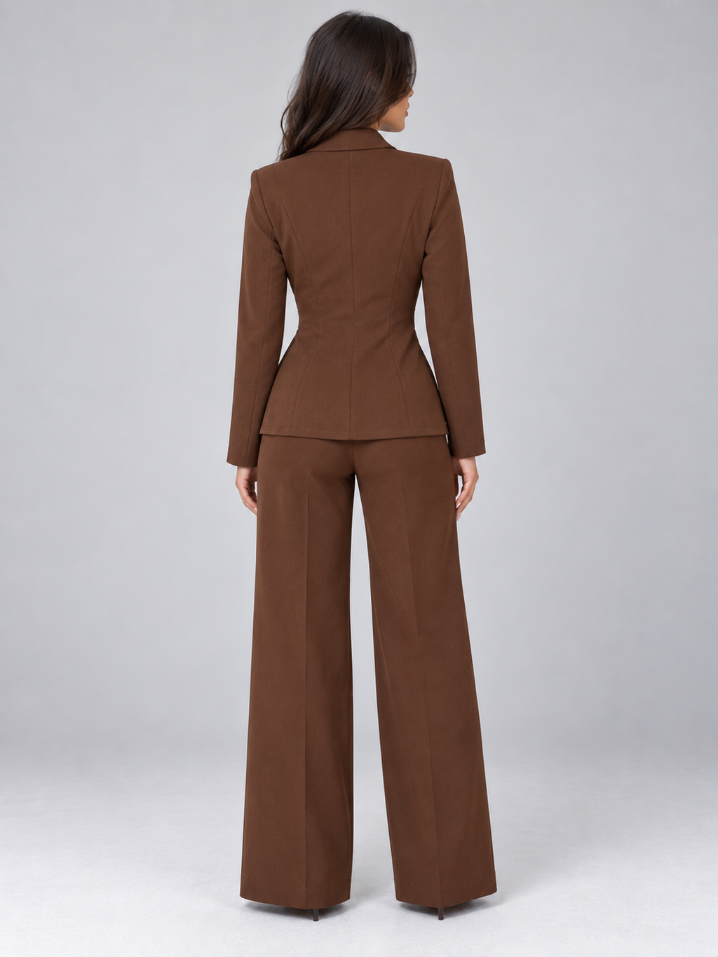Woman wearing brown belted blazer and wide leg trousers in tailored two-piece suit, back view