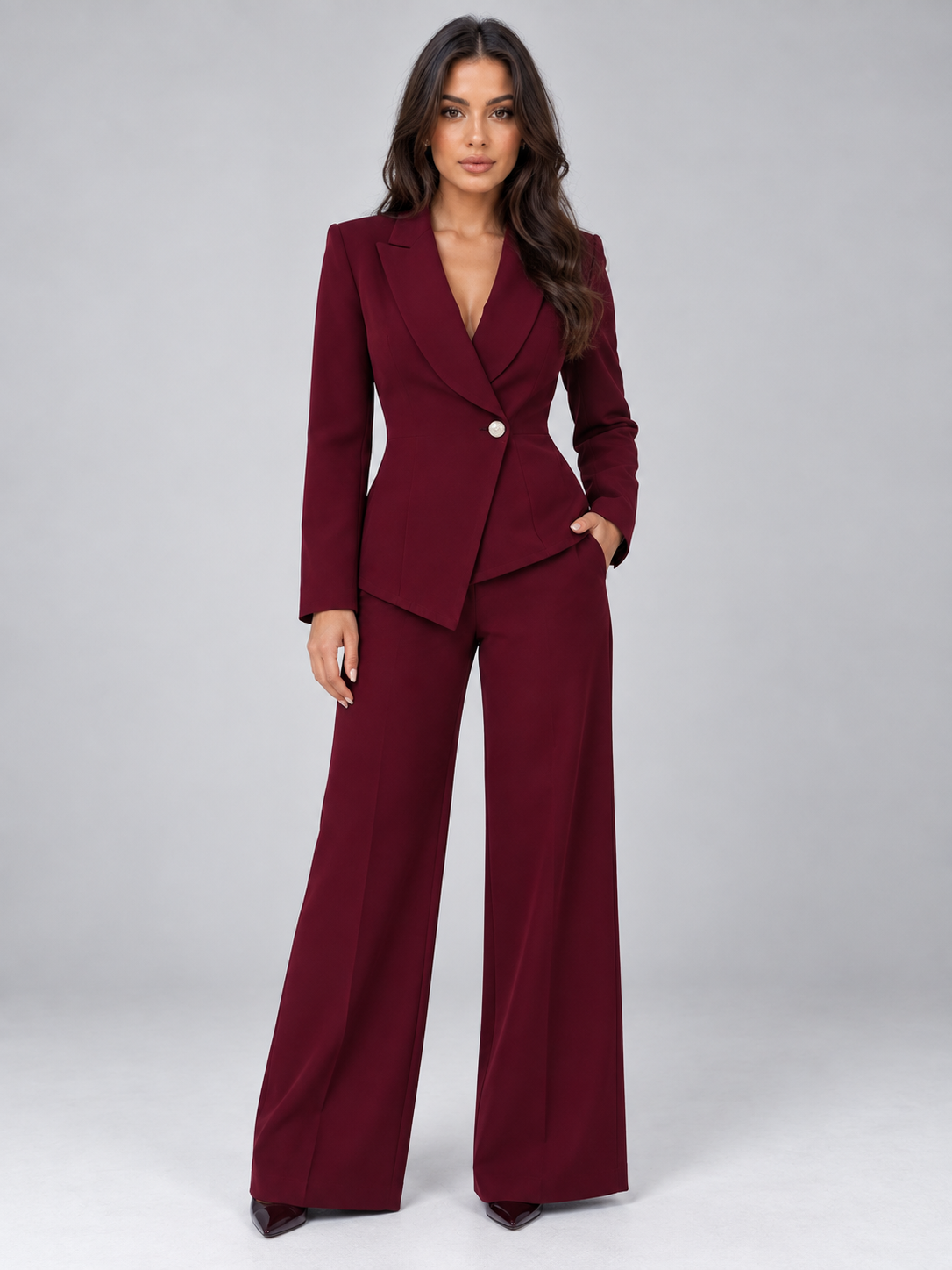 Woman wearing burgundy belted blazer with matching wide-leg trousers tailored two-piece suit on gray background