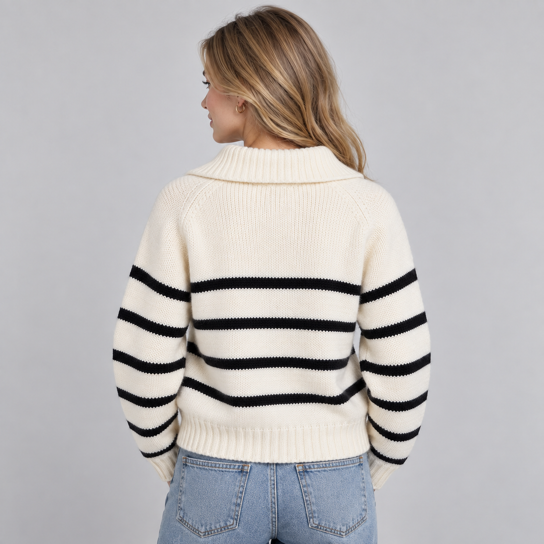 Woman wearing cream and black striped half zip funnel neck jumper with light blue jeans, back view