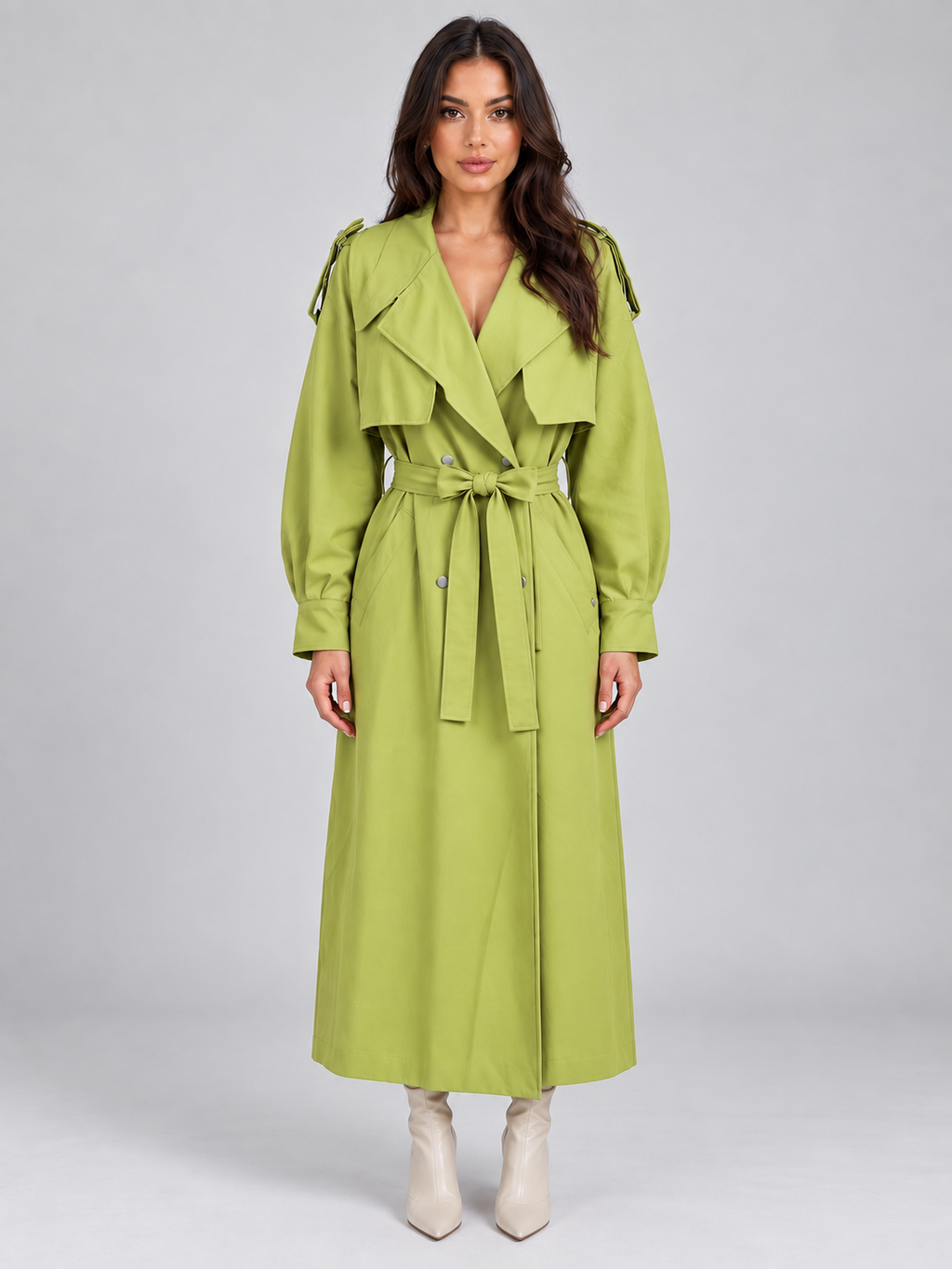 Woman wearing lime green belted trench coat with double-breasted front and puffed sleeves, paired with cream ankle boots