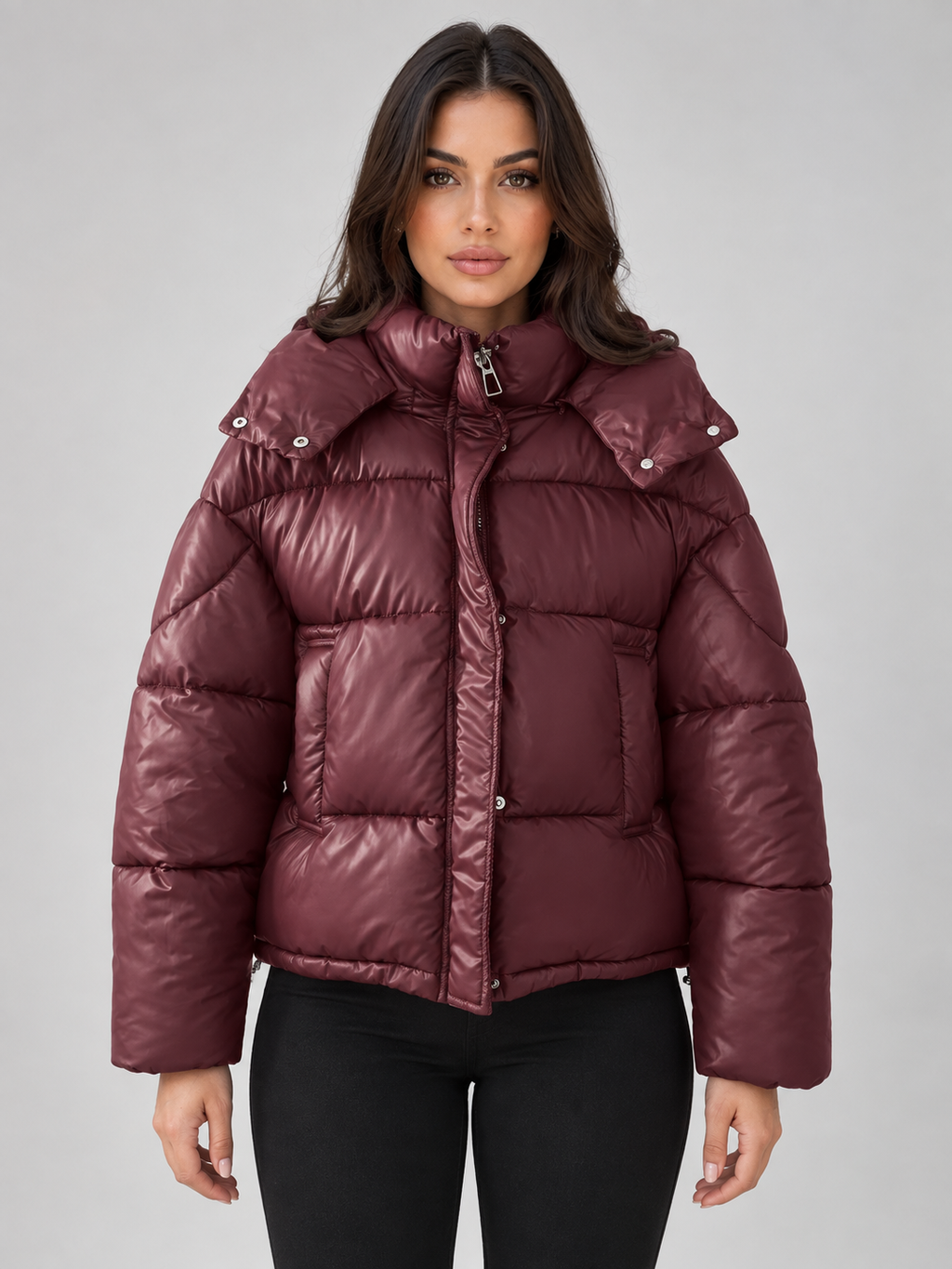Woman wearing burgundy padded puffer hooded jacket with black pants, full zip front closure and shoulder detailing