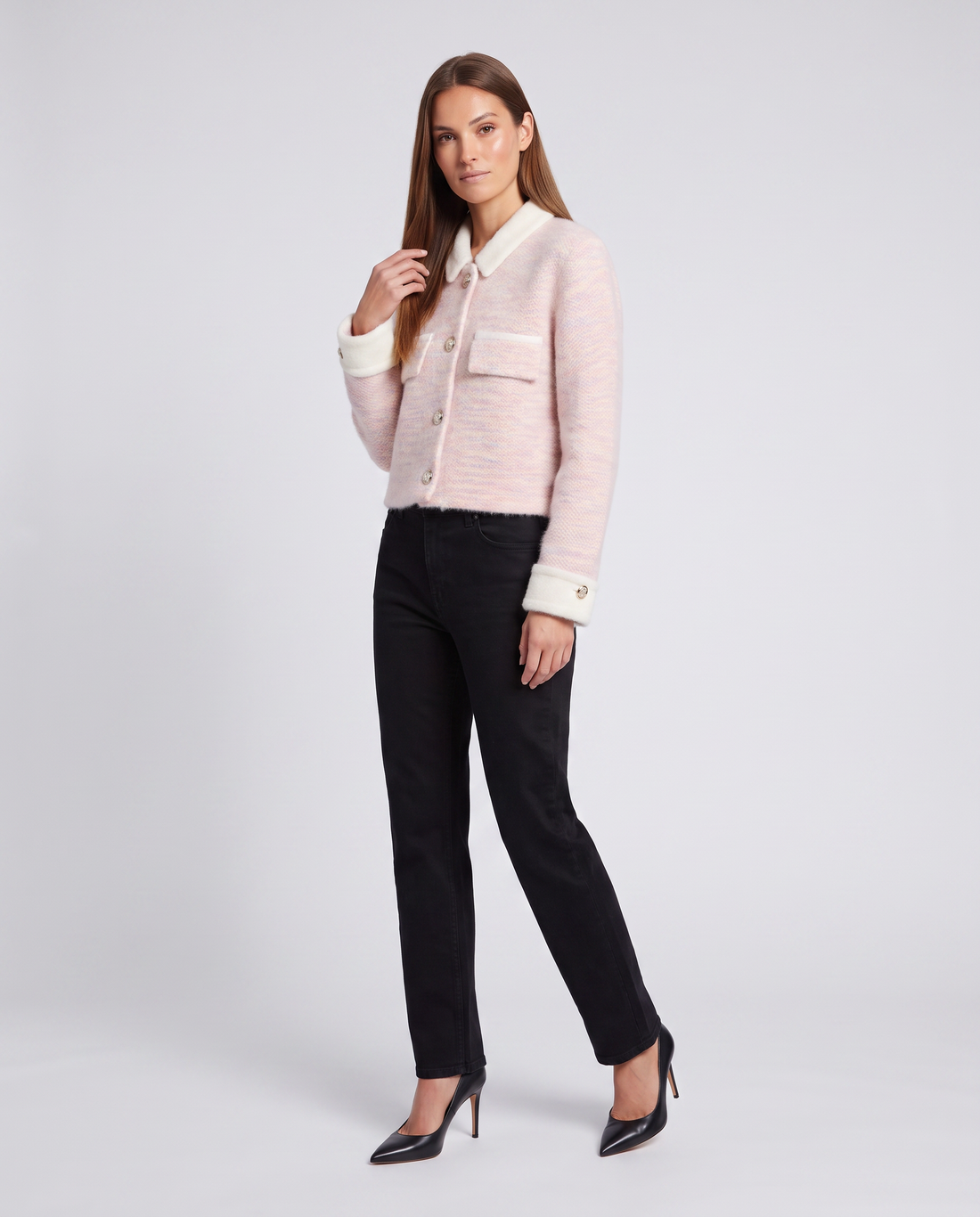 Woman wearing pink fuzzy cardigan with white contrast collar and cuffs, styled with black pants and black heels