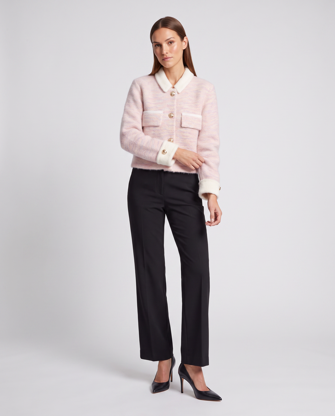 Woman wearing pink fuzzy cardigan with white collar and cuffs, paired with black straight-leg pants and black heels