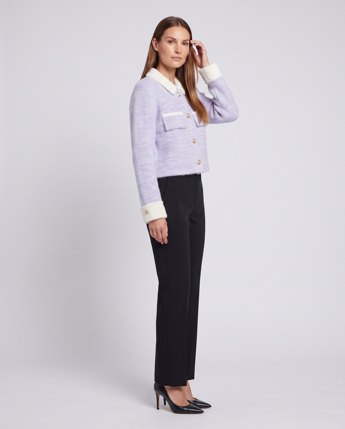 Woman wearing lavender fuzzy cardigan with white collar and cuffs, black trousers, and black pointed-toe heels