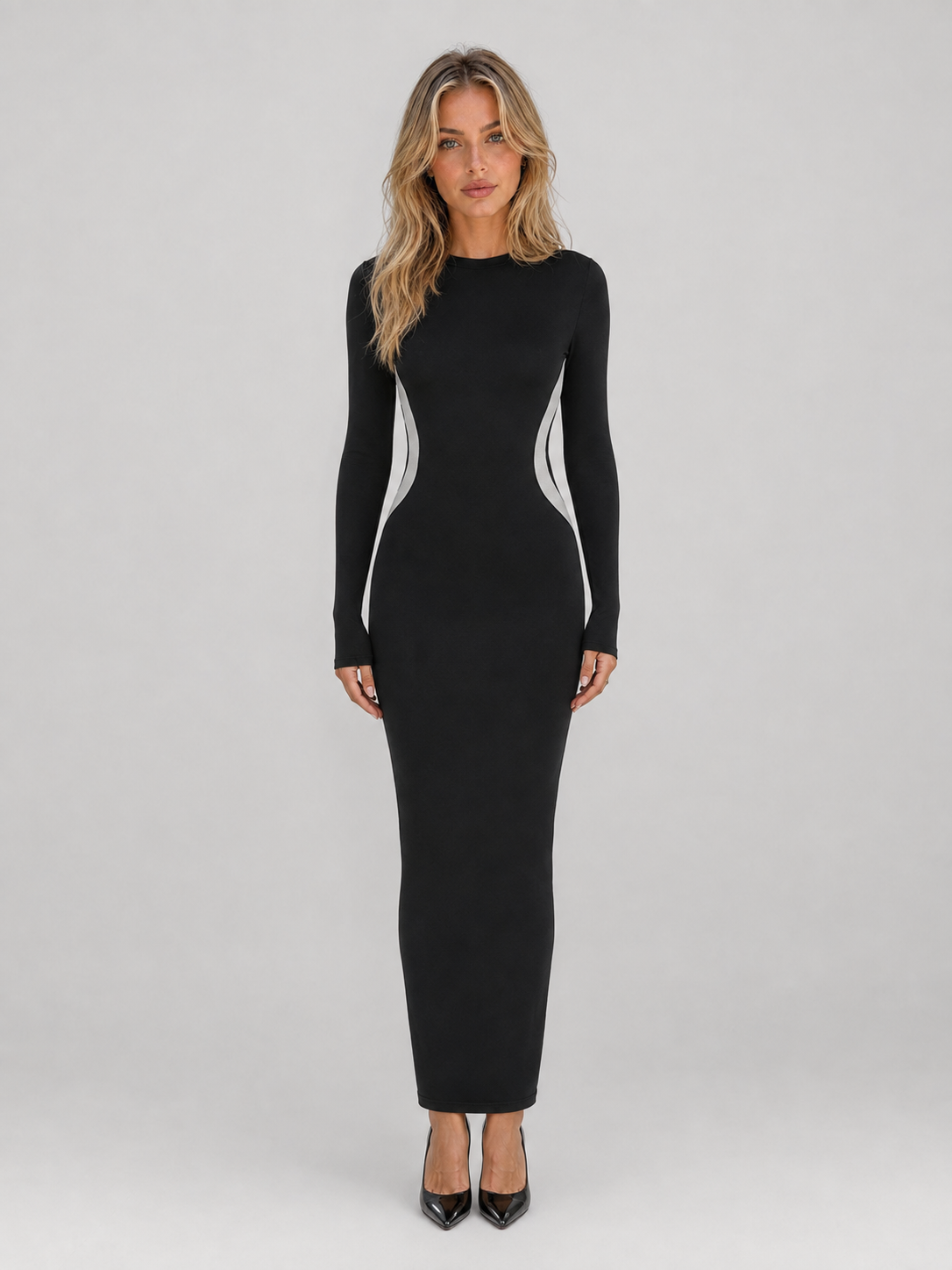 Women's black slim fit bodycon maxi dress with white side panels and long sleeves, modeled on gray background