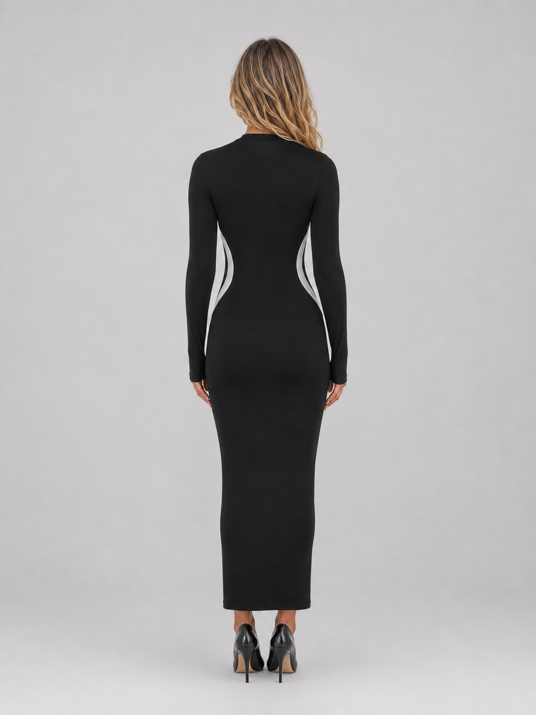 Woman wearing black slim fit bodycon maxi dress with white side panels and long sleeves, shown from back view wearing black heels